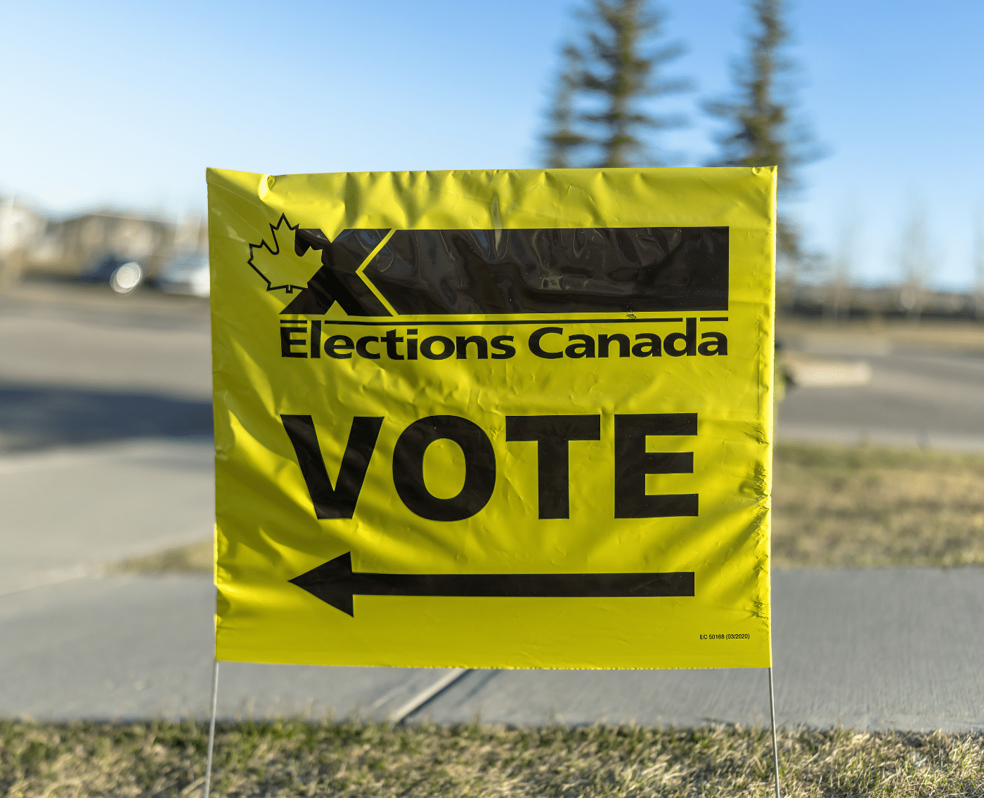 A vivid yellow sign from Elections Canada, displaying a maple leaf and bold black writing, signals a Canadian election voting site.
