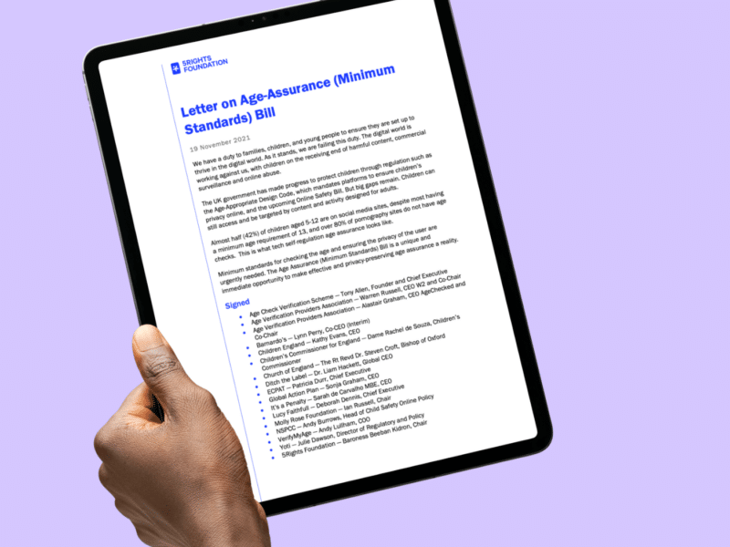 A hand holding a tablet displaying a document titled "Letter on Age-Assurance (Minimum Standards) Bill" by 5Rights Foundation. The letter outlines concerns and recommendations regarding age-assurance methods for protecting children online. It includes signatures from various organisations and individuals advocating for stronger regulations. The background is a soft purple, and the tablet is held upright, showcasing the text clearly.