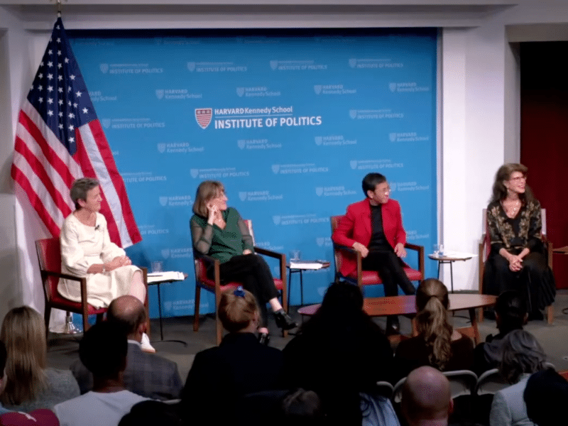 From left: Margrethe Vestager, Baroness Beeban Kidron, Maria Ressa, and Shoshana Zuboff. They are sat on a stage. There is a large US flag to the left, behind Margrethe Vestager. The backdrop is a pale blue with the logo and text 'Harvard Kennedy School: Institute of Politics'.