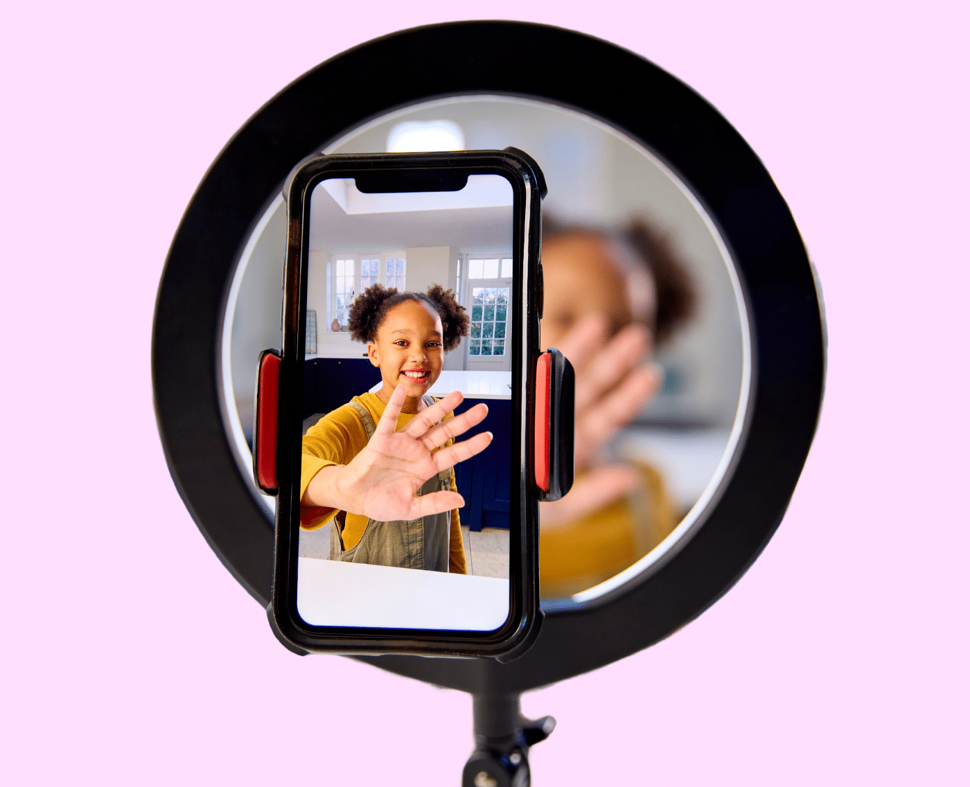  A young girl at home is recording a video with her smartphone to upload on social media. She looks happy and she is wearing brown overalls over a mustard-coloured shirt.