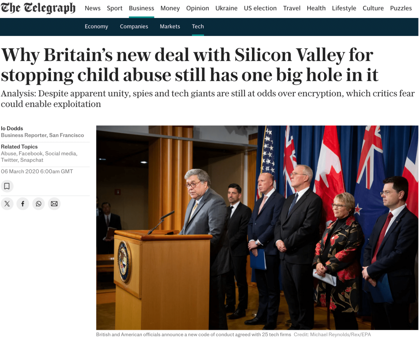 A screenshot of a news article from The Telegraph titled, "Why Britain’s new deal with Silicon Valley for stopping child abuse still has one big hole in it." The article, written by Io Dodds, discusses challenges between governments and tech giants regarding encryption and child abuse prevention. Below the headline is an image of a formal press conference with British and American officials standing on stage, including an official speaking at a podium. They are flanked by flags of the US, UK, and other countries.